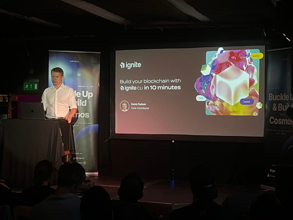 Denis at a lectern beside a slide reading “Build your blockchain with Ignite CLI in 10 minutes”