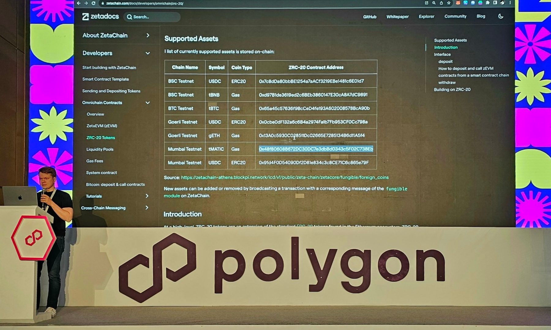 Denis at a lectern on the Polygon stage, presenting the ZetaChain docs